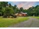 Log cabin home nestled in a wooded setting at dusk at 15717 Round O Rd, Round O, SC 29474