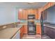 Modern kitchen with wood cabinets, black appliances, and neutral countertops at 140 Black River Dr, Summerville, SC 29485