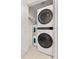 Stackable washer and dryer in a small laundry room with tile floor and shelving at 9681 Two Pines Rd, McClellanville, SC 29458