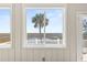 View from sunroom showcasing marsh, palm tree, and pier at 9681 Two Pines Rd, McClellanville, SC 29458