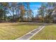 Large backyard with a concrete pathway, surrounded by trees and a wooden fence at 640 Old Back River Rd, Goose Creek, SC 29445