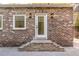 Brick exterior with a white door, accented by sconces and brick stairs at 278 Meeting St, Charleston, SC 29401