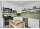 Modern kitchen with white cabinets, stainless steel appliances, a butcher block island, and green tile backsplash at 1001 Lango Ave, Charleston, SC 29407