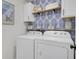 Laundry room with Whirlpool washer and dryer, white cabinets, and blue tropical wallpaper at 587 Tribeca Ct, Charleston, SC 29414