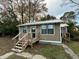 Quaint home with tan siding, a metal roof, and a wooden deck and stairs at 1808 Calvert St, North Charleston, SC 29405
