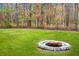 Stone fire pit in grassy backyard with wooded backdrop at 261 Old Carolina Dr, Goose Creek, SC 29445