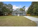 Gray house with white accents, a grassy lawn, and a paved driveway at 309 Meadow St, Walterboro, SC 29488