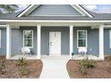 Front porch of a gray house features white columns and modern chairs at 309 Meadow St, Walterboro, SC 29488