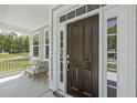 Dark brown front door with sidelights, welcoming porch with seating at 3 Wappoo Trace Ln, Summerville, SC 29486