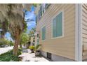 Side view of a charming yellow house with teal shutters and lush landscaping at 197 Coming St, Charleston, SC 29403