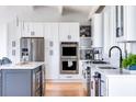 Modern kitchen boasts white cabinets, stainless steel appliances, and a large island at 403 Pelican Flight Dr, Dewees Island, SC 29451
