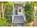 Inviting front porch with grey steps, landscaping and white columns at 1220 Middle St, Sullivans Island, SC 29482