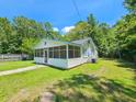 Side view of a white one-story house with a screened porch and green lawn at 212 Hickory St, Walterboro, SC 29488