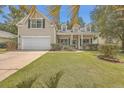 Attractive tan house with white garage door, landscaping, and a covered porch at 802 Long Drive Rd, Summerville, SC 29485