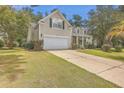 House exterior showcasing beige siding, a white garage door, and landscaping at 802 Long Drive Rd, Summerville, SC 29485