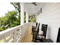 Spacious side porch with multiple rocking chairs, white railings, and a ceiling fan at 1056 Capersview Ct, Awendaw, SC 29429