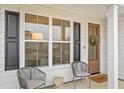 Charming front porch with gray wicker chairs, a wooden door, and black shutters at 416 Grove End Rd, Moncks Corner, SC 29461