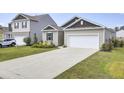 Tan house with a dark brown roof, white garage door, and landscaping at 182 Greenwich Dr, Summerville, SC 29486