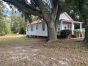 Side view of a white cottage nestled under a large oak tree at 507 E 5Th N St, Summerville, SC 29483