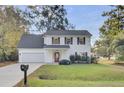 Two-story white house with a red door, attached garage, and manicured lawn at 1600 Windsor Ln, Moncks Corner, SC 29461