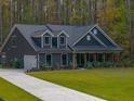 Gray farmhouse exterior with a wraparound porch and a large yard at 112 Canewood Ln, Ridgeville, SC 29472