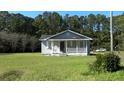 Gray house with white trim and porch, nestled in a wooded setting at 8266 N Highway 17, McClellanville, SC 29458
