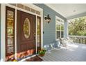 Front porch with a rich wooden door, white chairs, and colorful flowers at 5250 Timber Race Crse, Hollywood, SC 29449