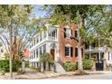 Brick three-story home with a wraparound porch and gated entrance at 52 Hasell St, Charleston, SC 29401