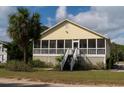 Front view of yellow house with screened porch and palm tree at 2302 Palmetto Blvd, Edisto Beach, SC 29438
