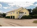 Side view of yellow house with screened porch and white stairs at 2302 Palmetto Blvd, Edisto Beach, SC 29438