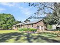 Brick ranch house with a metal roof, nestled on a spacious lot with mature trees at 203 Hickory Nut Drive, Harleyville, SC 29448