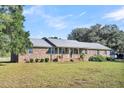 Brick ranch house with metal roof and landscaped yard at 203 Hickory Nut Drive, Harleyville, SC 29448