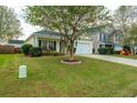 Landscaped yard with a tree, and yellow house with white garage at 323 Bradley Bend Dr, Moncks Corner, SC 29461