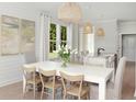 White farmhouse dining table with light wood chairs, situated near kitchen at 746 Blue Iris Way, Summerville, SC 29486