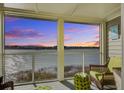 Relaxing screened porch with wicker furniture and stunning sunset views over the water at 30 Mariners Cay Dr, Folly Beach, SC 29439