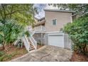 Elevated home with a detached garage and wooden stairs leading to the entrance at 317 W Hudson Ave, Folly Beach, SC 29439