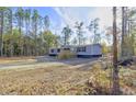 Manufactured home in a wooded setting with a gravel driveway at 1523 Harmony Hall Ln, Round O, SC 29474