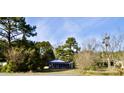 Ranch home with blue trim, situated on a spacious lot with mature trees at 8146 N Highway 17, McClellanville, SC 29458