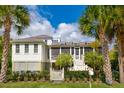 White house with screened porch, landscaping, and palm trees at 2220 Ion Ave, Sullivans Island, SC 29482