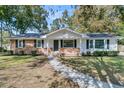 Charming ranch home with brick and white siding, showcasing a well-maintained lawn and walkway at 115 Camelia Dr, Summerville, SC 29485