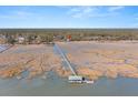 Aerial view of waterfront property with a long pier leading to a covered structure at 9681 Two Pines Rd, McClellanville, SC 29458
