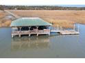 Covered waterfront boat dock with a floating pier, perfect for enjoying the water at 9681 Two Pines Rd, McClellanville, SC 29458