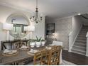 Dining room featuring a large round mirror, a wooden table with place settings, and a staircase at 610 Red Monarch Way, Moncks Corner, SC 29461