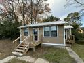 Quaint home with tan siding, a metal roof, and a wooden deck and stairs at 1808 Calvert St, North Charleston, SC 29405