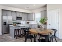 Modern kitchen with gray cabinets, granite island, and wooden dining table at 764 Meadowbrook Ln, Summerville, SC 29486