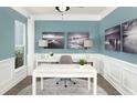 Bright home office features white desk, wood floors, and calming blue walls at 147 Royal Cainhoy Way, Huger, SC 29450