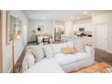 Open living room and kitchen with white sectional sofa and wood floors at 303 Tiliwa Street, Summerville, SC 29486