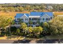 Large home with a blue roof and palm trees, situated near water at 8 Seagrass Ln, Isle of Palms, SC 29451