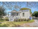 Quaint white cottage with a metal roof, front porch, and gravel driveway at 1328 Cottonwood St, Charleston, SC 29403