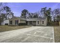 Tan house with dark shutters, large driveway, and mature trees at 115 Marion Rd, Summerville, SC 29486